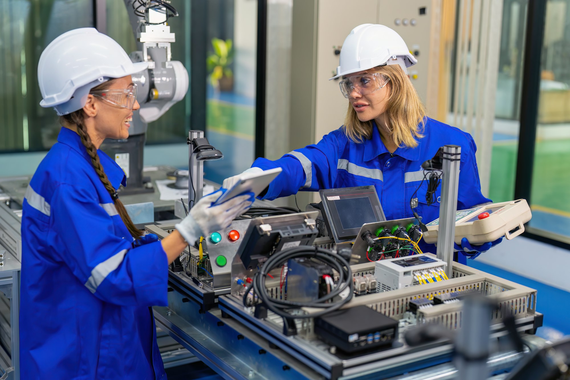 Female Electronics Factory Workers use tablet pc quality checking Circuit Boards after assembly